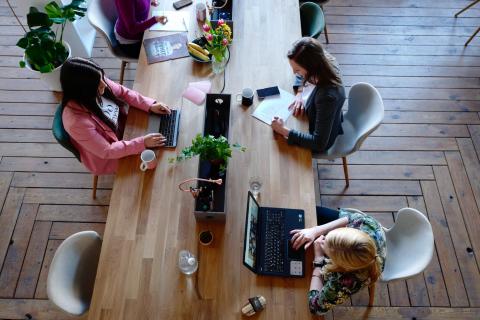 Overhead shot of women sitting at a wooden desk working