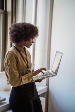 Black woman holding a laptop and typing